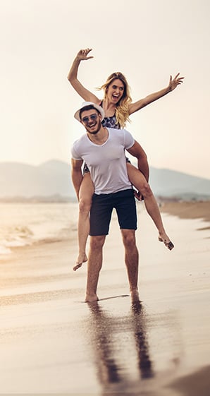 Young active couple on the beach illustrating the non-invasive nature of CoolSculpting with no down time (unlike liposuction)